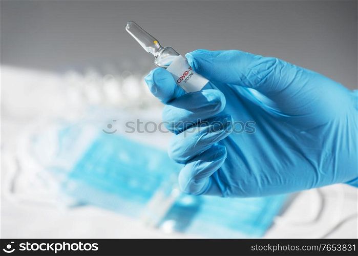 Coronavirus vaccine concept: covid-19 vaccine in hand with blue protective gloves.. Coronavirus vaccine concept