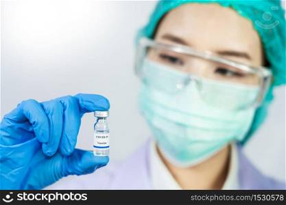 Coronavirus vaccine COVID-19 bottle for injection in hand of doctor or Technician scientist in a protective suit, Antiviral Healthcare And Medical Biological hazard concept.