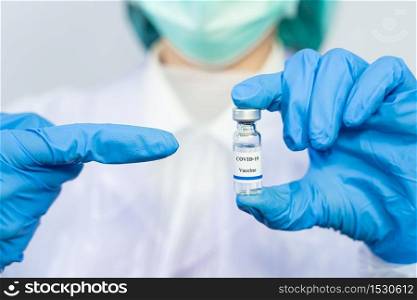 Coronavirus vaccine COVID-19 bottle for injection in hand of doctor or Technician scientist in a protective suit, Antiviral Healthcare And Medical Biological hazard concept.