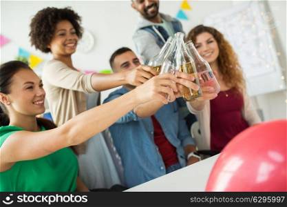 corporate, celebration and holidays concept - happy coworkers clinking bottles with non-alcoholic drinks at office party. happy team with drinks celebrating at office party
