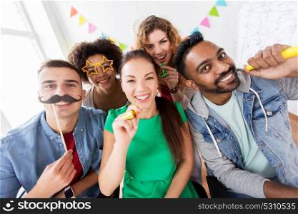 corporate, celebration and holidays concept - happy friends or team with party accessories having fun at office. happy friends or team having fun at office party