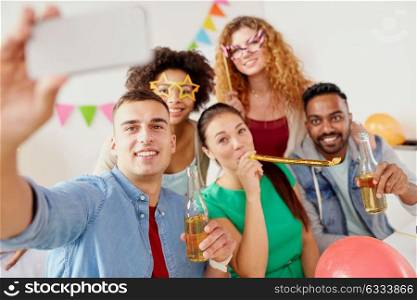 corporate, celebration and holidays concept - happy friends or team with party accessories and non alcoholic drinks taking selfie at office. happy team taking selfie at office party