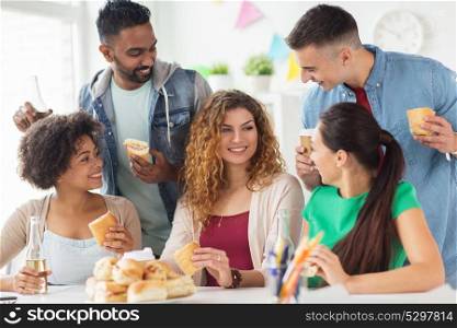 corporate, celebration and people concept - happy friends or team eating sandwiches with coffee and non-alcoholic drinks at office party. happy friends or team eating at office party