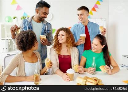 corporate, celebration and people concept - happy friends or team eating sandwiches with coffee and non-alcoholic drinks at office party. happy friends or team eating at office party