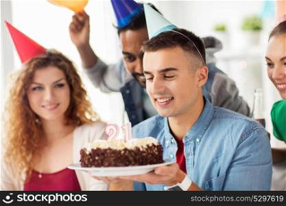 corporate, celebration and people concept - happy man with birthday cake and team making wish at office party. man with birthday cake and team at office party