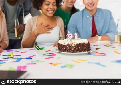 corporate, celebration and people concept - happy team with cake at office party greeting coworker with twenty first birthday. team greeting coworker at office birthday party