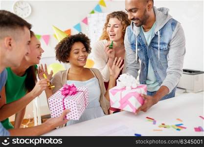 corporate, celebration and people concept - happy team with gifts greeting female colleague at office birthday party. team greeting colleague at office birthday party