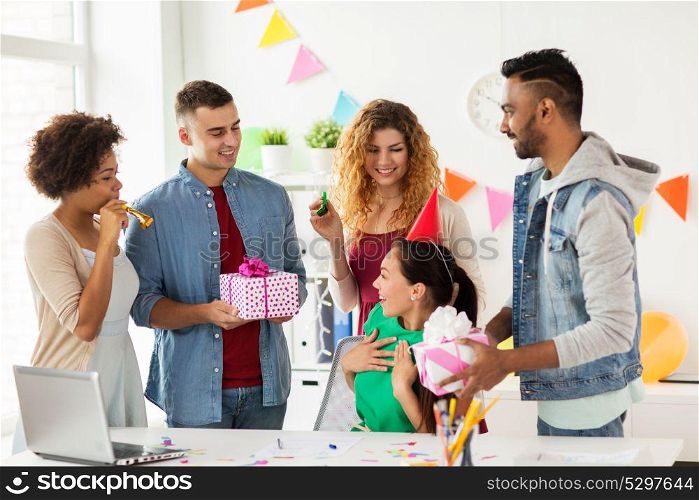 corporate, celebration and people concept - happy team with gifts greeting surprised colleague at office birthday party. team greeting colleague at office birthday party