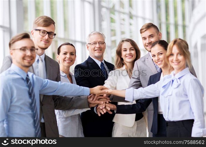 corporate, people and teamwork concept - happy business team stacking hands at office. happy business people stacking hands at office