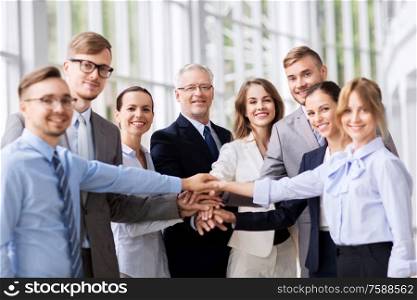 corporate, people and teamwork concept - happy business team stacking hands at office. happy business people stacking hands at office