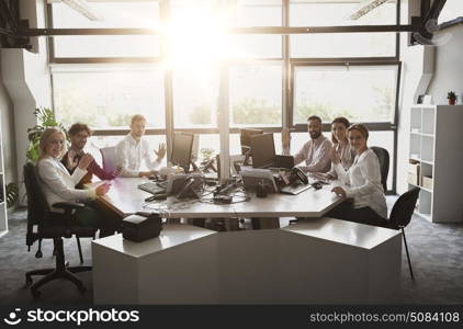 corporate, technology and people concept - business team with smartphones and computers waving hands at office. business team waving hands at office. business team waving hands at office