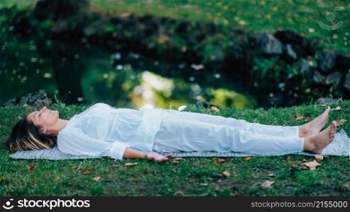 Corpse Position, Savasana, Meditation. Young woman practicing yoga and meditating by the water.. Corpse Position, Savasana, Meditation