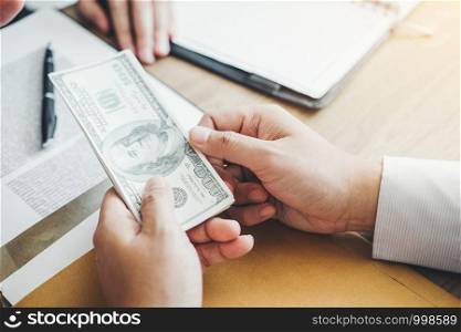 Corruption concept,Business man passing money dollar bills corruption bribery to businessman manager