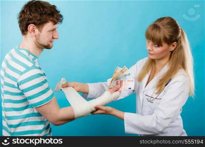 Corruption in healthcare industry. Female doctor bandaging male hand. Man giving money to woman. Bribery in medicine.. Female doctor bandaging male hand.