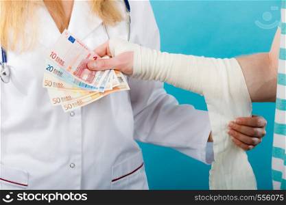 Corruption in healthcare industry. Female doctor bandaging male hand. Man giving money to woman. Bribery in medicine.. Female doctor bandaging male hand.