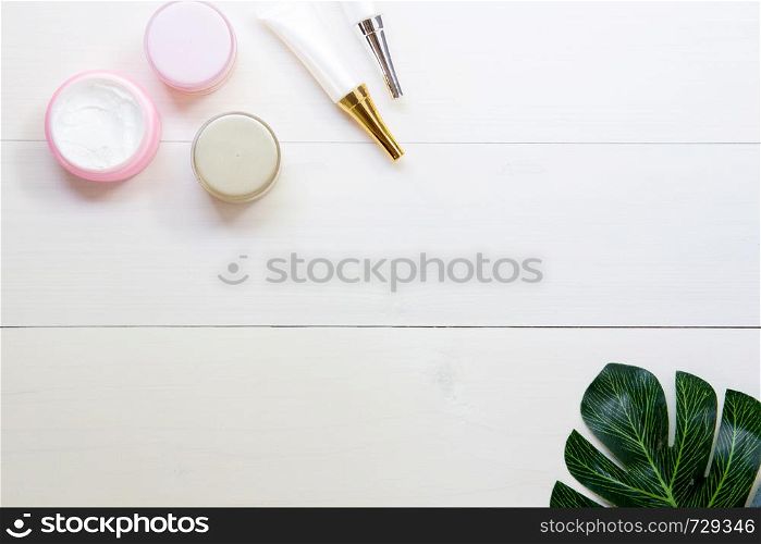 cosmetic and skin care product and green leaves on white wood table, beauty with treatment cream and moisturizing on wooden desk, health and wellness concept, top view.