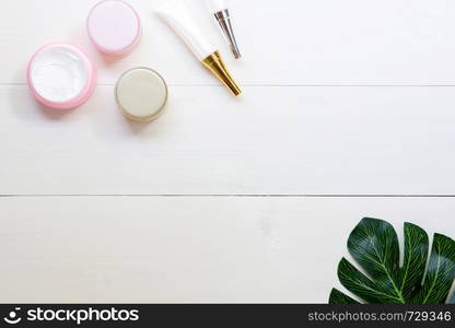 cosmetic and skin care product and green leaves on white wood table, beauty with treatment cream and moisturizing on wooden desk, health and wellness concept, top view.