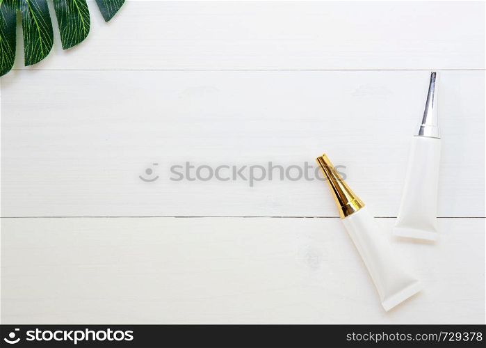 cosmetic and skin care product and green leaves on white wood table, beauty with treatment cream and moisturizer on wooden desk, health and wellness concept, top view.