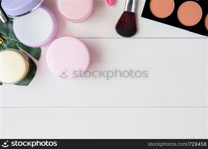 cosmetic and skin care product and green leaves on white wood table, beauty with treatment cream and moisturizer on wooden desk, health and wellness concept, top view.