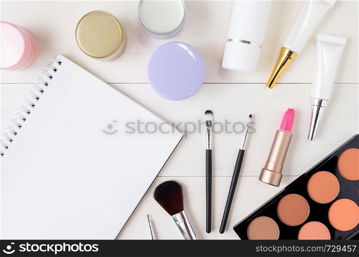 cosmetic and skin care product and notebook on white wood table, beauty with treatment cream and moisturizing and notepad copy space on wooden desk, health and wellness concept, top view.