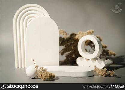 Cosmetic background for product presentation. White empty plaster podium and dried flowers on gray background. Background for product presentation.