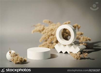 Cosmetic background for product presentation. White empty plaster podium and dried flowers on gray background. Background for product presentation.