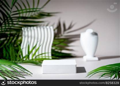 Cosmetic background for product presentation. White empty plaster podium with green palm leaves and shadows on biege background. Background for product presentation.