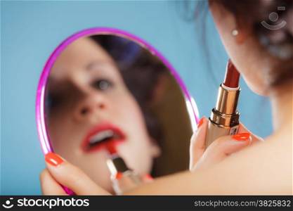 Cosmetic beauty procedures and makeover concept. Closeup part of woman face. Girllooking at mirror applying red lipstick lips makeup