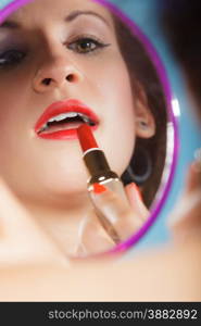 Cosmetic beauty procedures and makeover concept. Closeup part of woman face. Girllooking at mirror applying red lipstick lips makeup