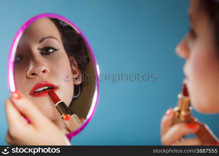 Cosmetic beauty procedures and makeover concept. Closeup part of woman face. Girllooking at mirror applying red lipstick lips makeup