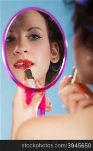 Cosmetic beauty procedures and makeover concept. Closeup part of woman face. Girllooking at mirror applying red lipstick lips makeup