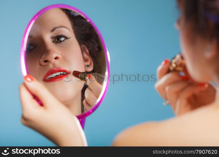 Cosmetic beauty procedures and makeover concept. Closeup part of woman face. Girllooking at mirror applying red lipstick lips makeup