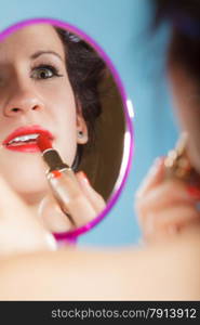 Cosmetic beauty procedures and makeover concept. Closeup part of woman face. Girllooking at mirror applying red lipstick lips makeup