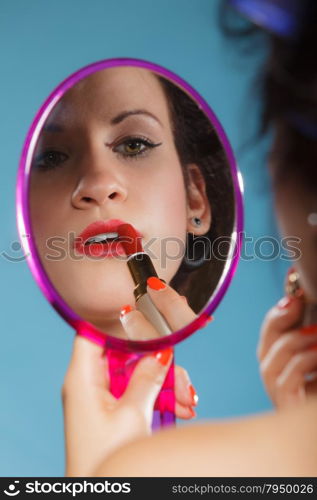 Cosmetic beauty procedures and makeover concept. Closeup part of woman face. Girllooking at mirror applying red lipstick lips makeup