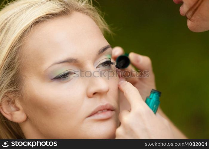 Cosmetic beauty procedures and makeover concept. Closeup part of woman face eye makeup detail. Make up artist applying mascara.