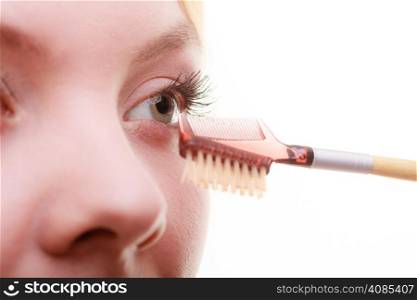 Cosmetic beauty procedures and makeover concept. Closeup part of woman face eye makeup detail. Using comb to separate lashes after applying mascara, long eyelashes.