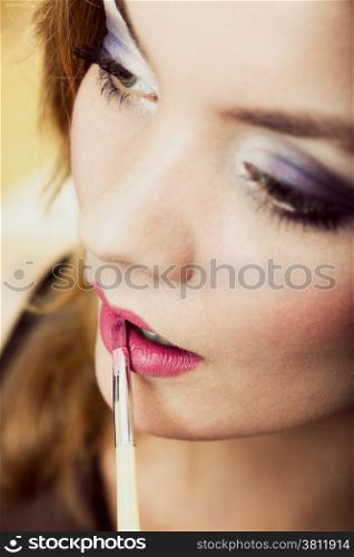 Cosmetic beauty procedures and makeover concept. Closeup part of woman face pink lips. Make-up artist applying lipstick with accessories tools.