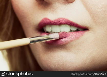 Cosmetic beauty procedures and makeover concept. Closeup part of woman face pink lips. Make-up artist applying lipstick with accessories tools.