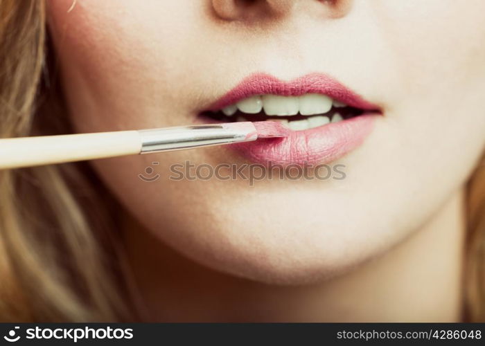 Cosmetic beauty procedures and makeover concept. Closeup part of woman face pink lips. Make-up artist applying lipstick with accessories tools.