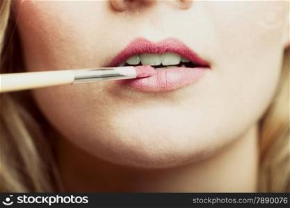Cosmetic beauty procedures and makeover concept. Closeup part of woman face pink lips. Make-up artist applying lipstick with accessories tools.