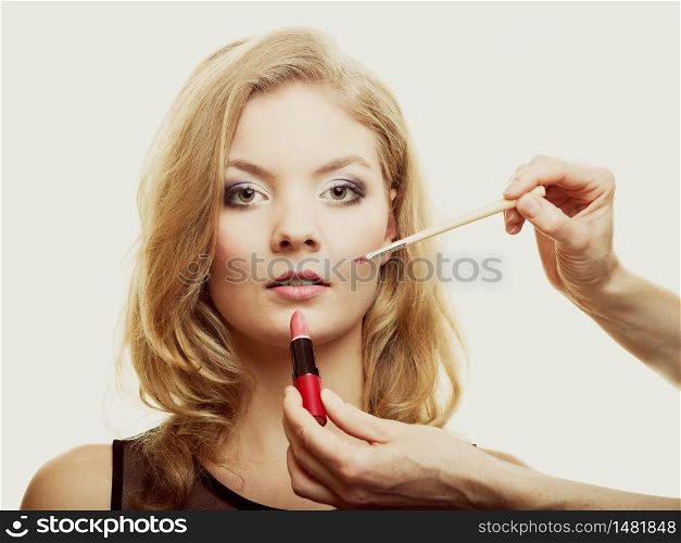 Cosmetic beauty procedures and makeover concept. Makeup artist applying lipstick with accessories tools to woman lips.