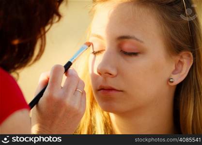 Cosmetic beauty procedures and makeover concept. Makeup artist applying with brush color eyeshadow on female eye.