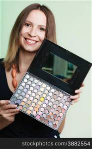 Cosmetic beauty procedures and makeover concept. Woman holds makeup professional palette. Make-up applying. Green background