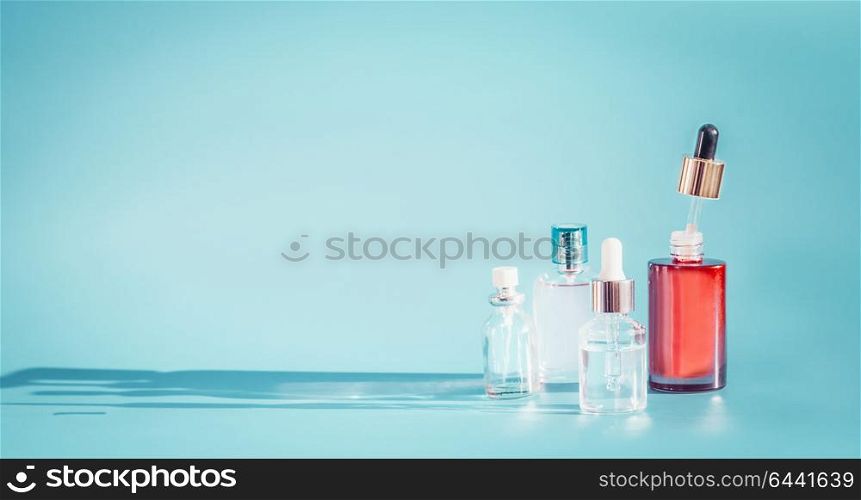 Cosmetic bottle products with liquid, pipette at blue background, front view. Essence, toner or extract serum on table, front view. Beauty and modern skin care concept with copy space