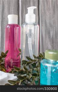 Cosmetic bottles on a gray background in the back with a green sprig.. Cosmetic bottles on a gray background with a green sprig.