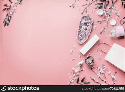 Cosmetic concept. Facial skin care products and paper shopping bag on pastel pink background with cherry blossom and leaves, top view, frame. Copy space for your design. Beauty blog layout. Flat lay