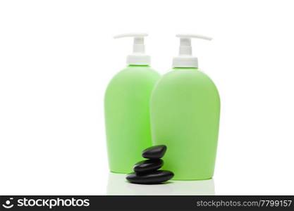 cosmetic containers and spa black stones isolated on white