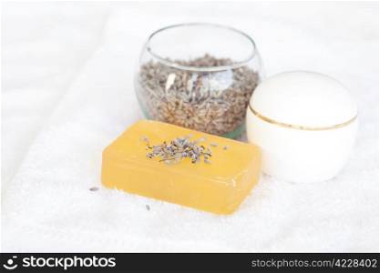 cosmetic containers, soap and lavender on a white towel
