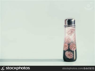 Cosmetic liquid product bottle with flowers essence or toner on light mint background, front view, copy space. Beauty product concept. Blank label for branding mock-up