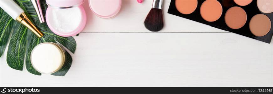 cosmetic makeup and skin care product and leaves on white wood table, beauty with treatment cream and moisturizer copy space on wooden desk, health and wellness concept, top view, banner website.